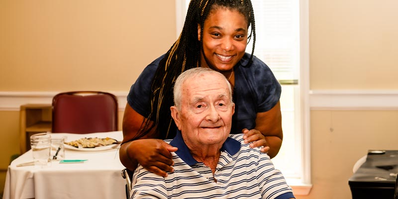 Elderly man and caregiver posing for the camera.