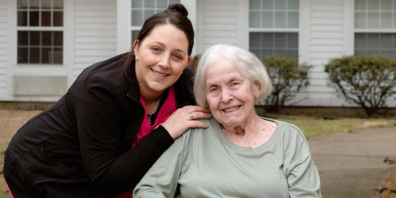 Elderly woman and caregiver posing for the camera.