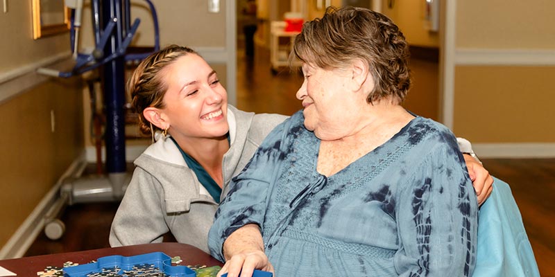 Caregiver smiling with elderly resident